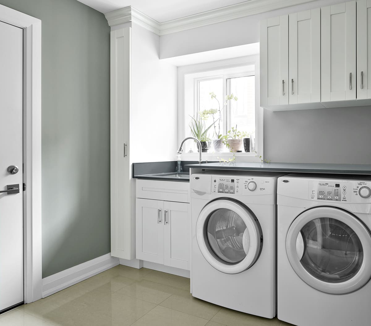 Washer and dryer in laundry room renovation with tile flooring and undermount sink by Master Edge Homes