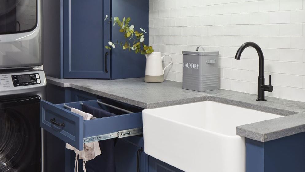 aging in place laundry room with navy blue cabinets with open drawer towel drying hanger in clean and modern laundry room with mosaic tiling with undermount sink in markham ontario