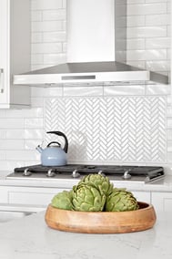 artichokes in bowl on marble kitchen island and herringbone tile backsplash and range hood in markham kitchen renovation